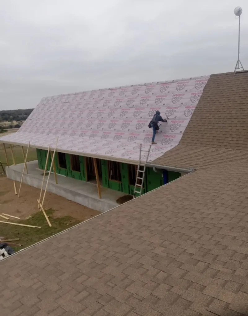 Worker preparing underlayment for a metal roof installation in San Juan Capistrano